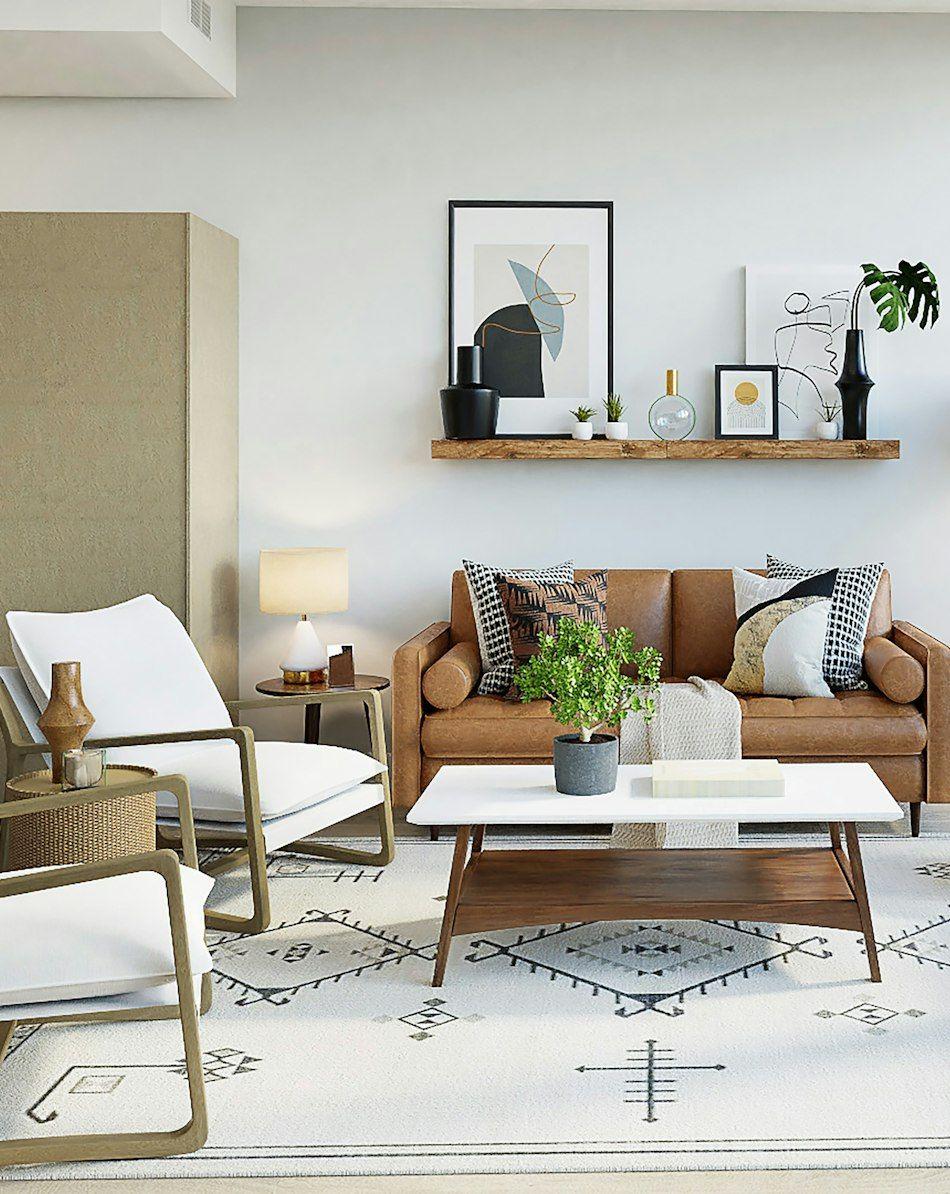 Living room with a tan leather sofa, white lounge chairs and a floating shelf of artwork
