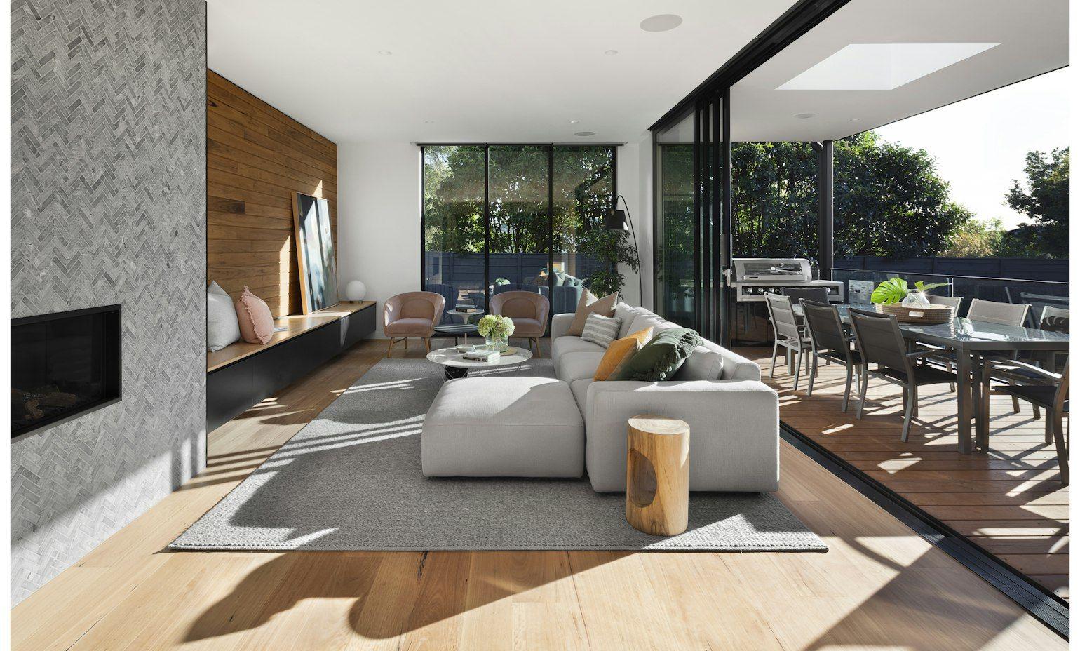 Open-plan lounge with a herringbone stone fireplace wall, timber cladding and sliding doors to a deck