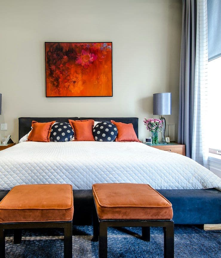 Bedroom with upholstered headboard and orange ottomans