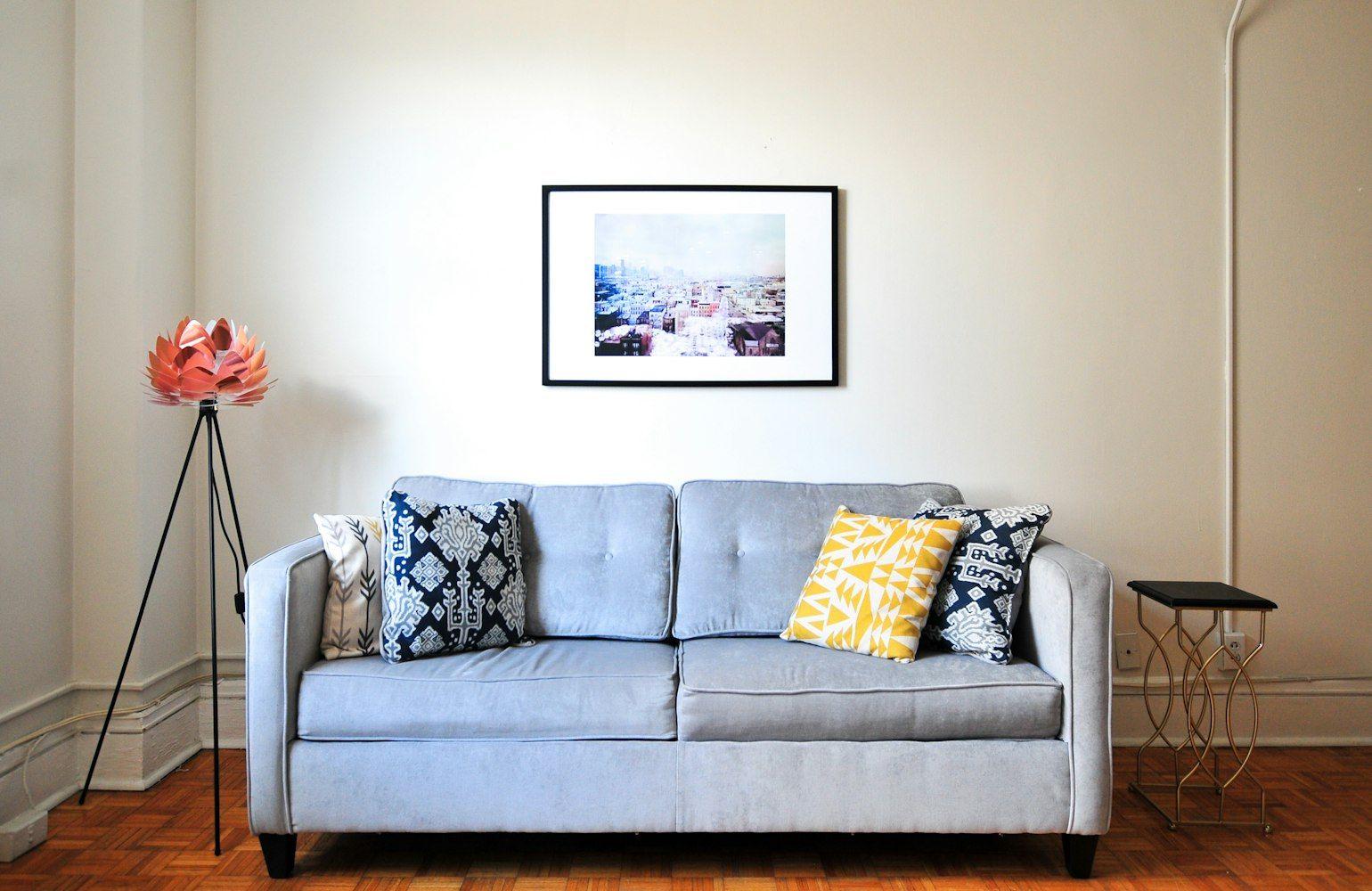 Light grey sofa with patterned cushions against a white wall