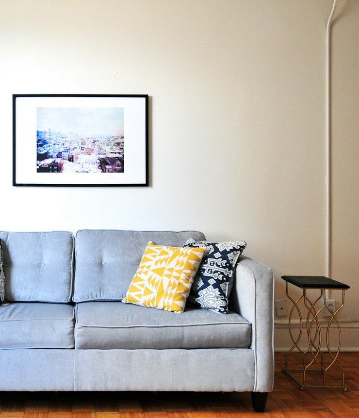Light grey sofa with patterned cushions against a white wall
