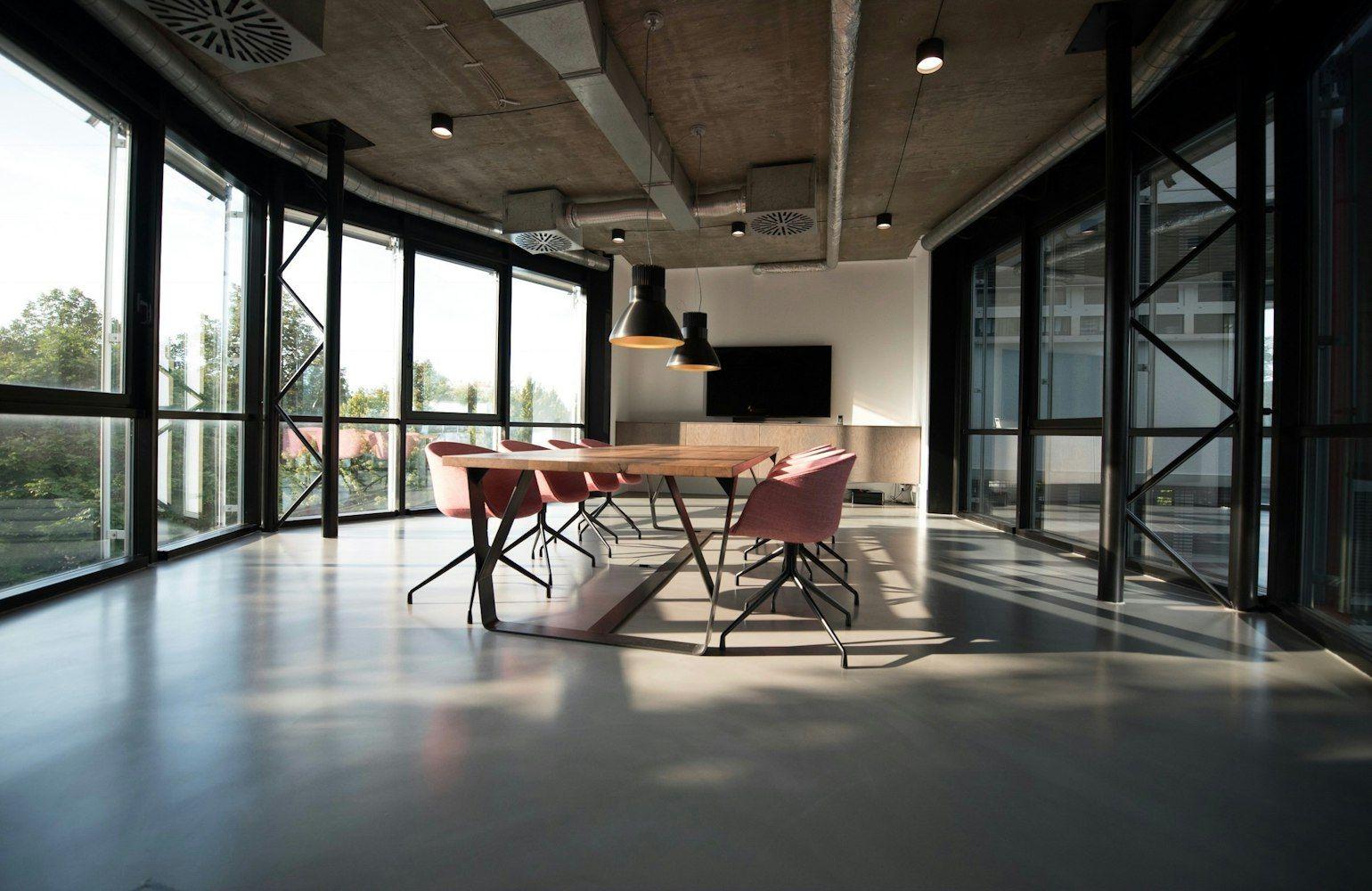 Open office with long timber tables and black pendant lights